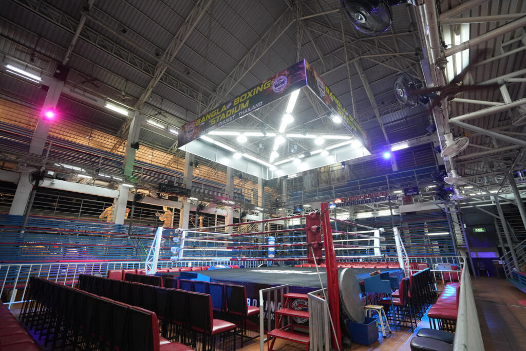 Wide view inside Bangla Boxing Stadium with the ring under the venue sign and tiered seating