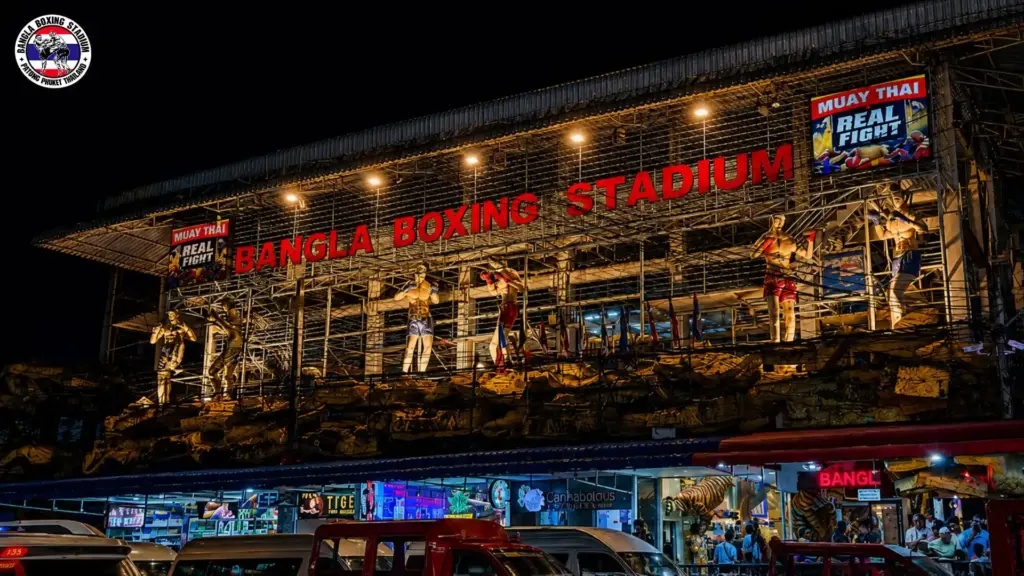 Bangla Stadium Patong at night with lit red signage and Muay Thai fighter statues on the balcony