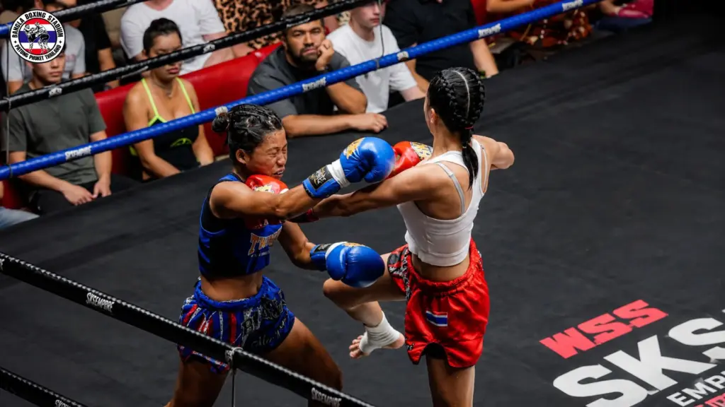 Two female fighters exchanging fierce strikes during a competitive Muay Thai Patong live match.