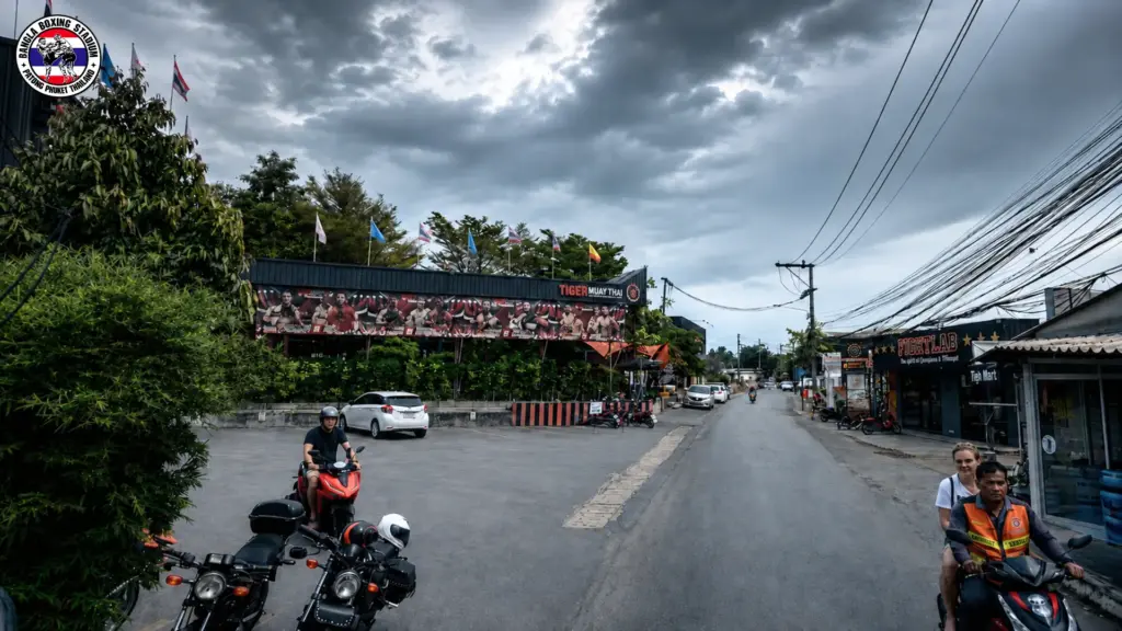 Street view of Tiger Muay Thai gym in Phuket with signage and motorbikes parked outside
