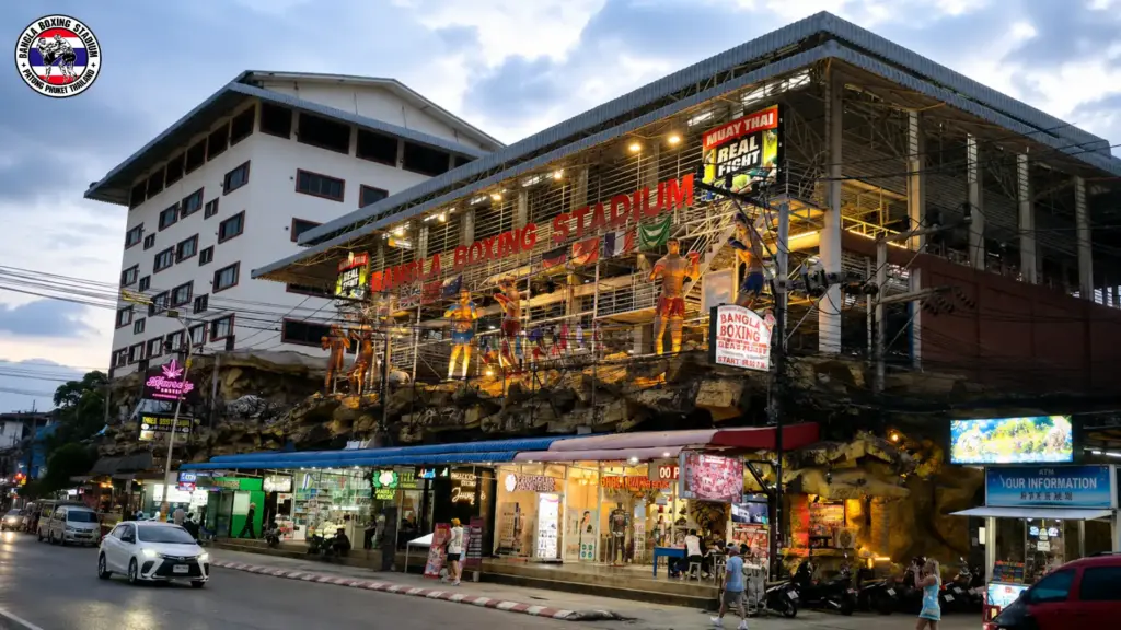 Bangla Boxing Stadium exterior in Phuket featuring Muay Thai fighter statues and illuminated signs.
