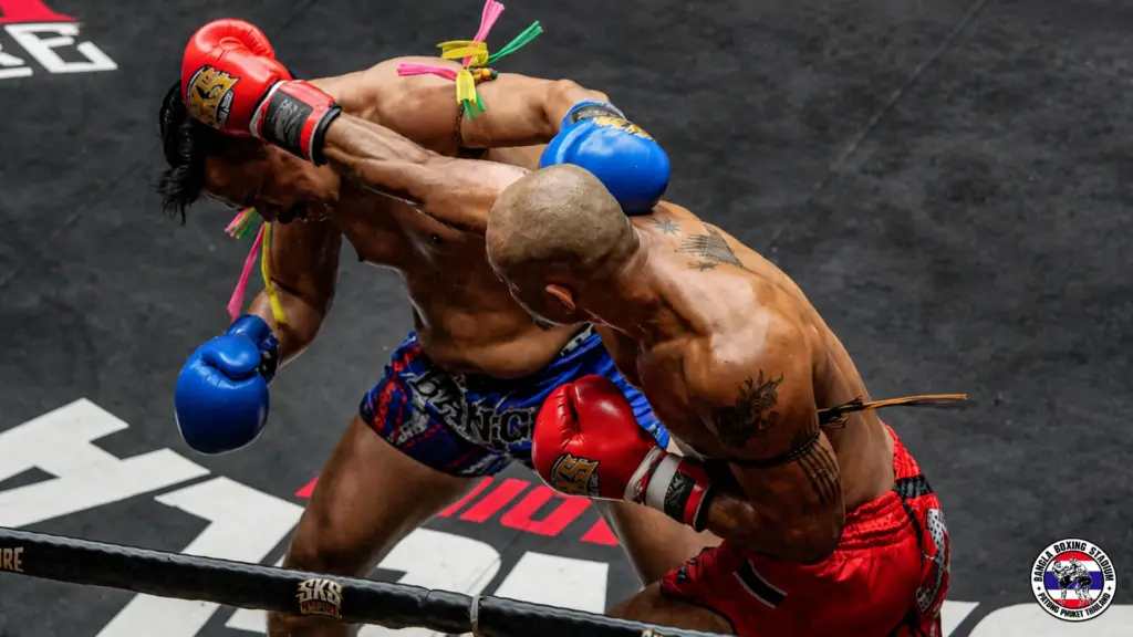 Professional Muay Thai fighters engaged in close combat during a match at a Phuket stadium
