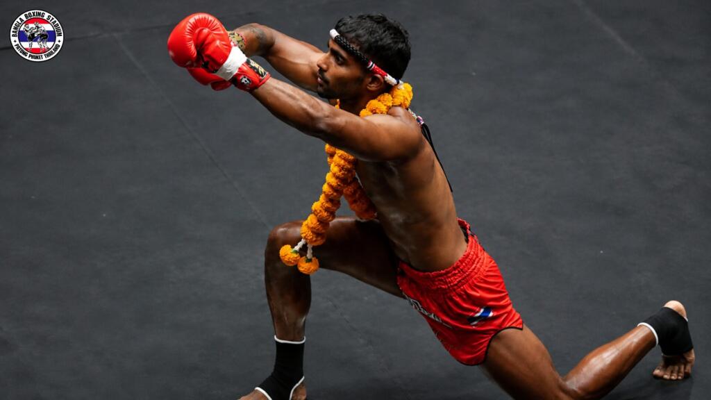 Muay Thai fighter in red gloves and a flower garland performing the Wai Kru ritual