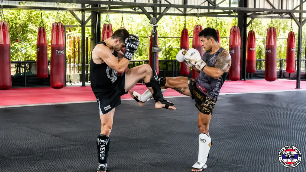 Muay Thai athletes sparring and practicing kicks at a training gym in Thailand