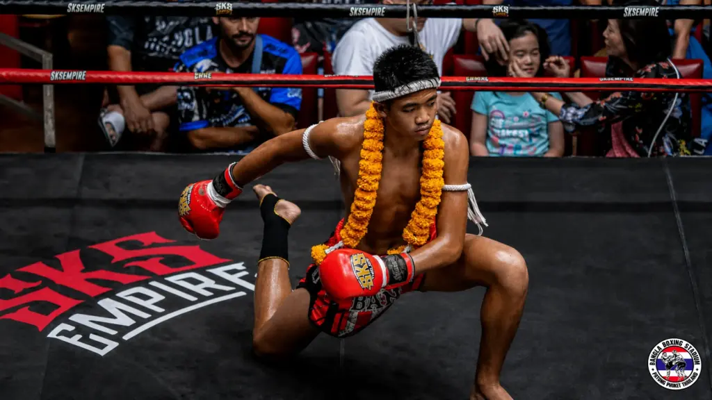 Muay Thai boxer performing the Wai Kru ritual with a flower garland before a match