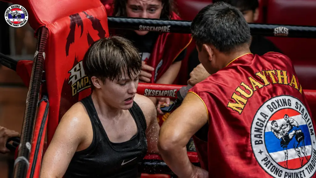 Female Muay Thai fighter resting in her corner between rounds at Bangla Boxing Stadium