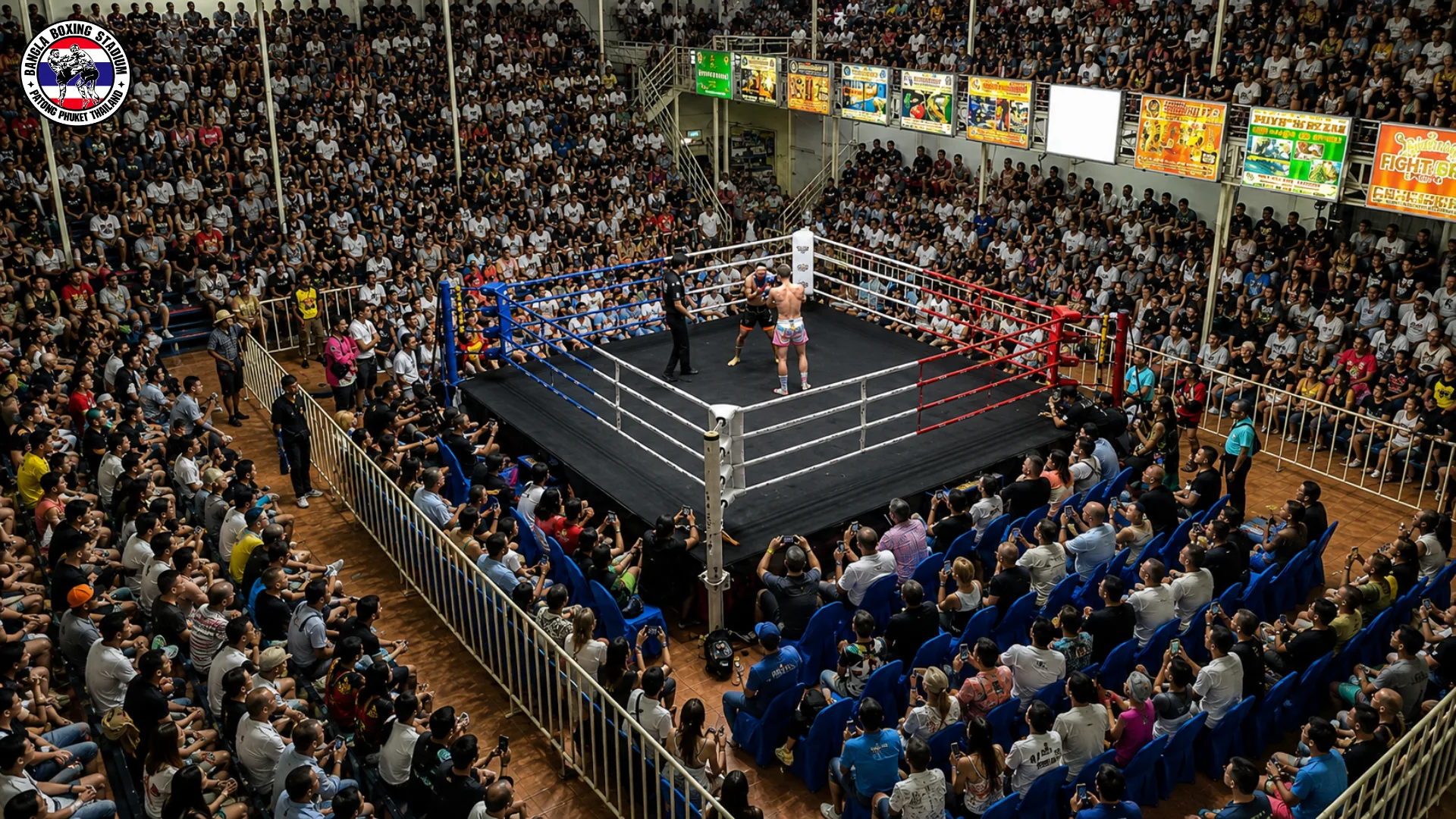 Packed muay thai stadium seen from above with a bout underway in the ring