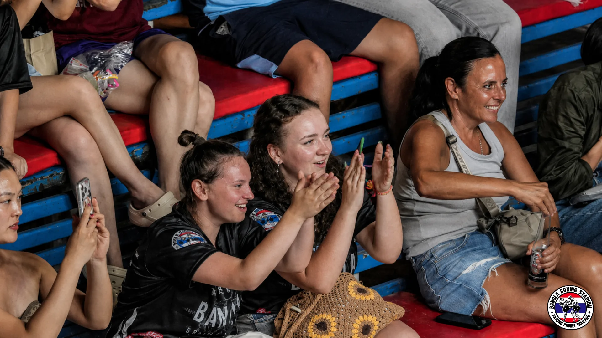 Spectators cheering from the stands during a live muay thai fight night