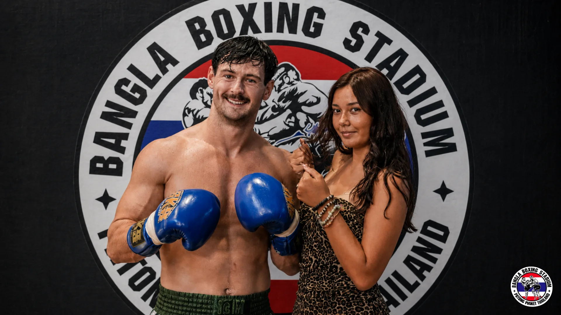 Visitors with boxing gloves at the Bangla Boxing Stadium logo wall in Patong