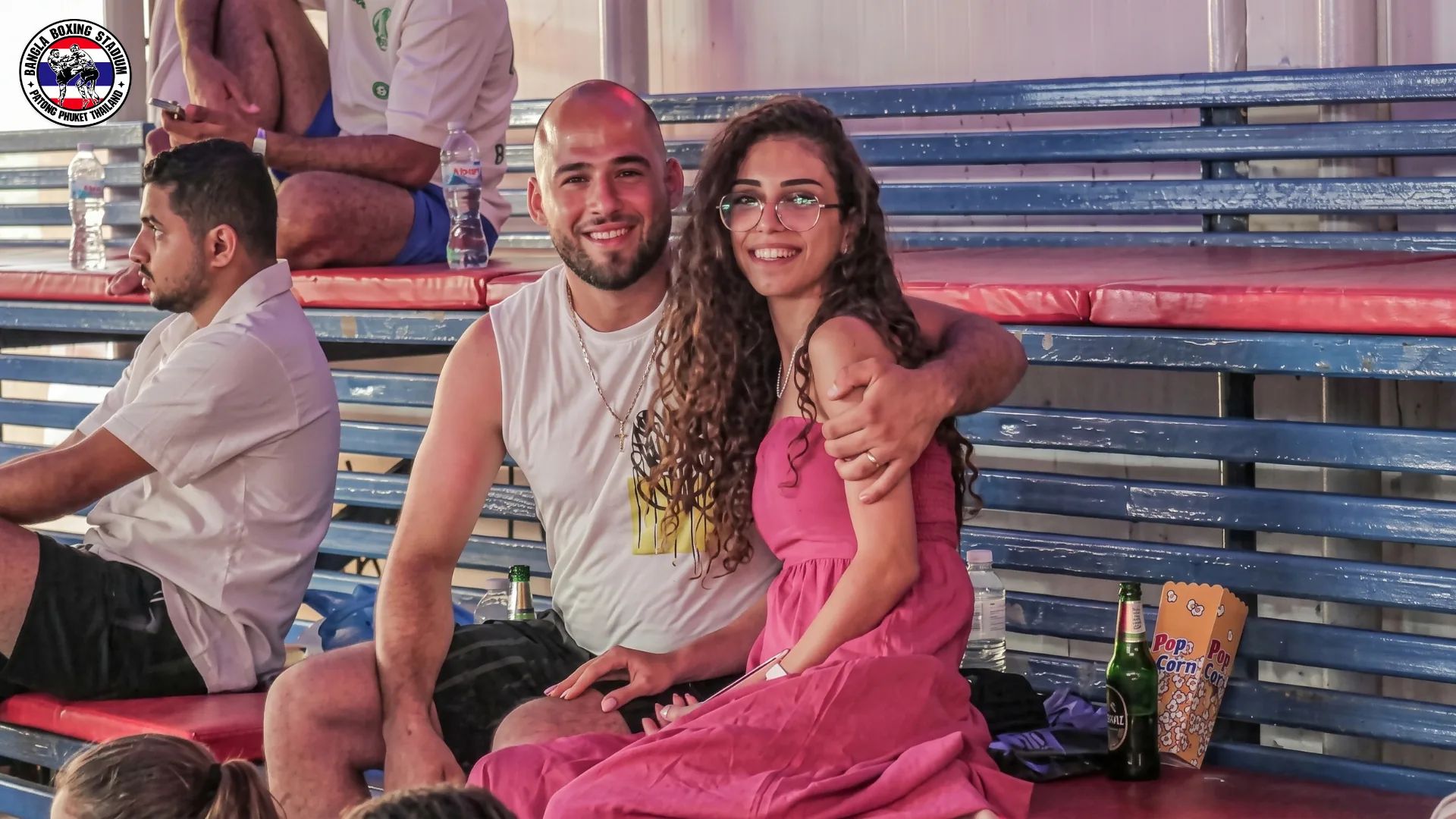 Couple with a beer and popcorn in the stands at Bangla Boxing Stadium
