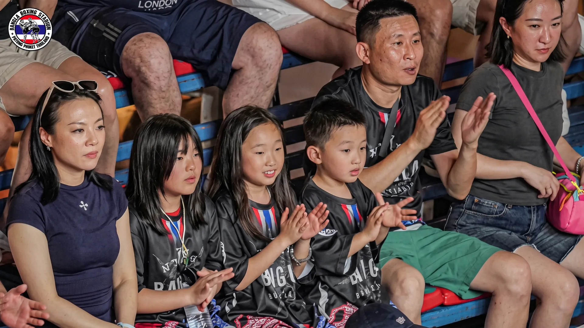 Family with young children clapping during a Muay Thai bout in Patong