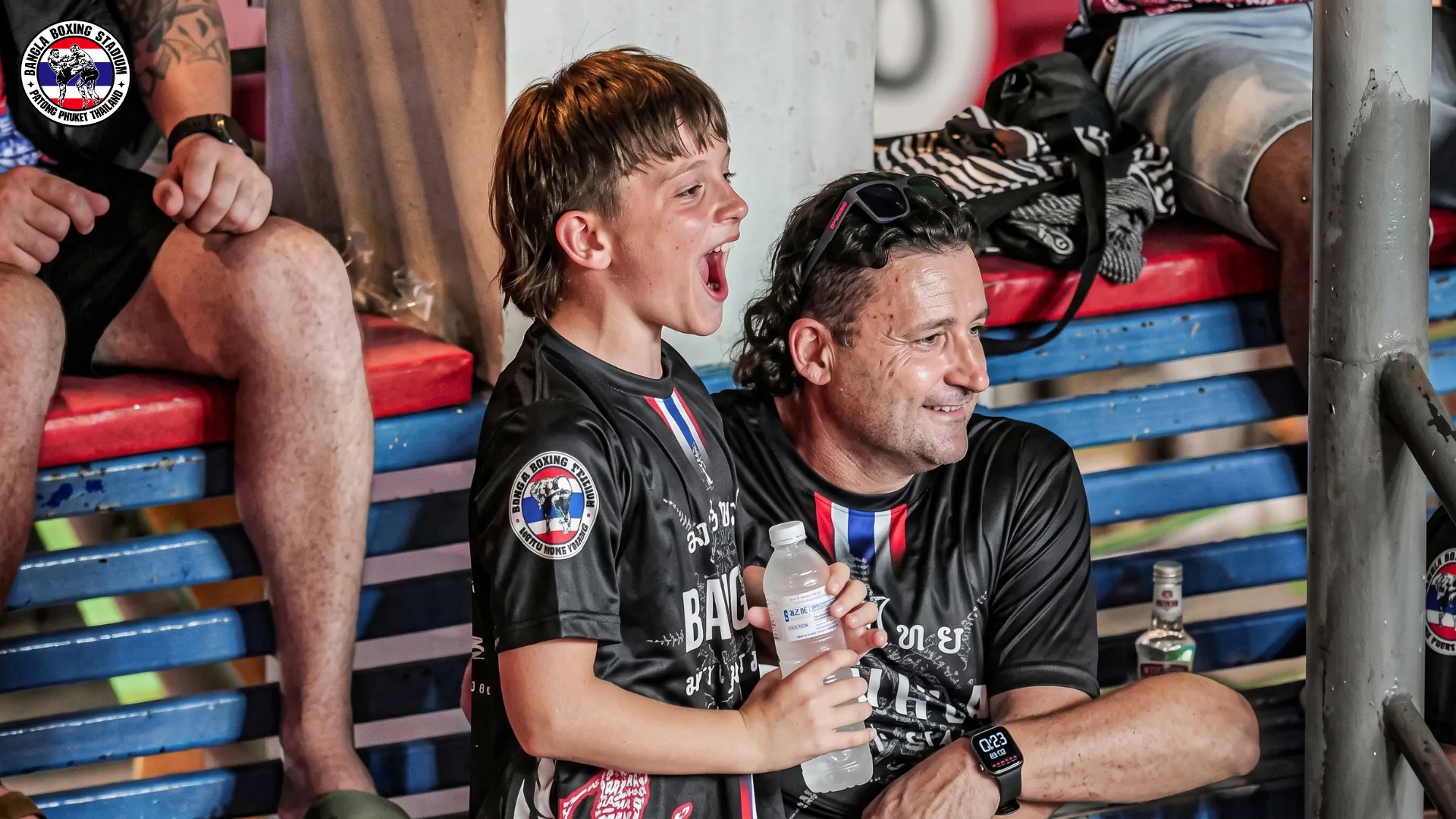 Father and son cheering at a Muay Thai family night at Bangla Boxing Stadium