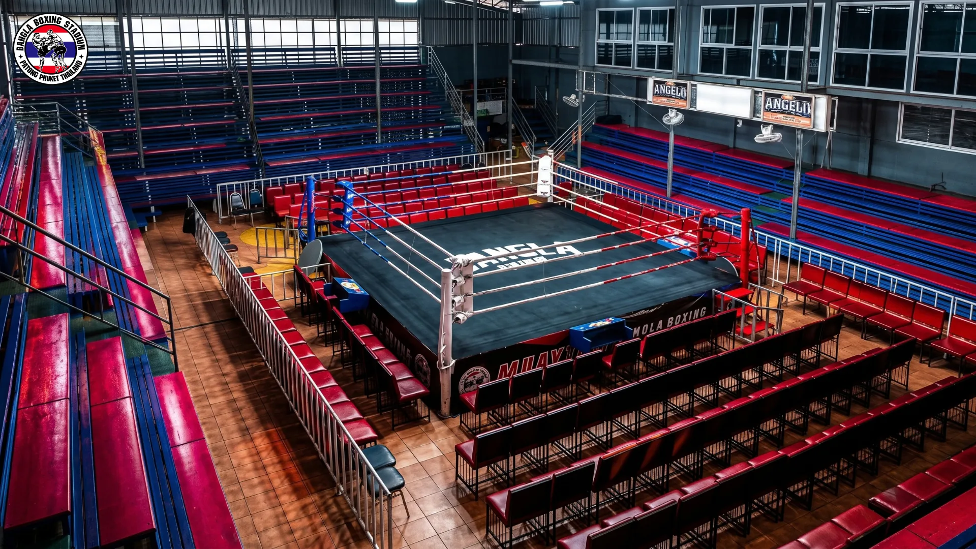 Wide view of the ring, ringside chairs and stadium seating inside Bangla Boxing Stadium