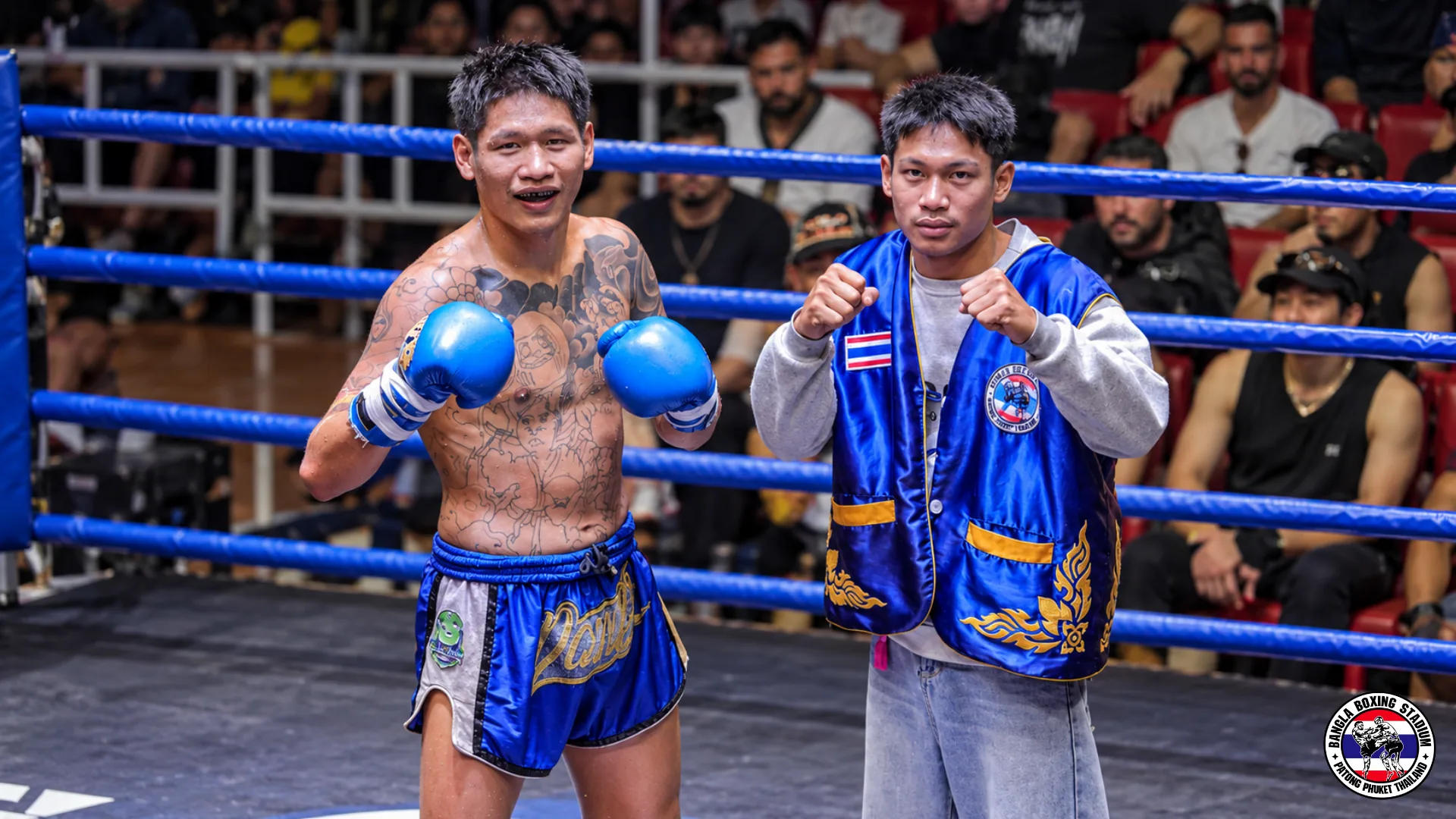 Muay Thai fighter in blue shorts posing in the ring after the bout