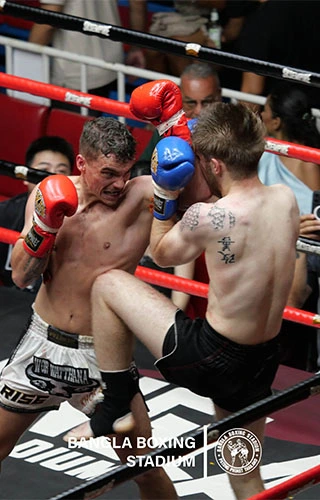 Two Muay Thai fighters trading punches in the ring at Bangla Boxing Stadium